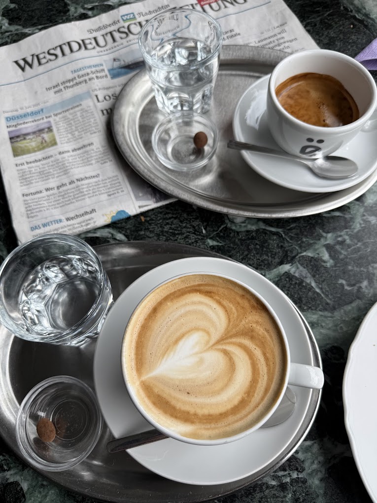 Innenraum der Rösterei Lamëng in Düsseldorf-Unterrath, grüne Wand mit hölzerner Weltkarte, gemütliche Sitzecken, Bistro-Theke mit Espressomaschine im Hintergrund