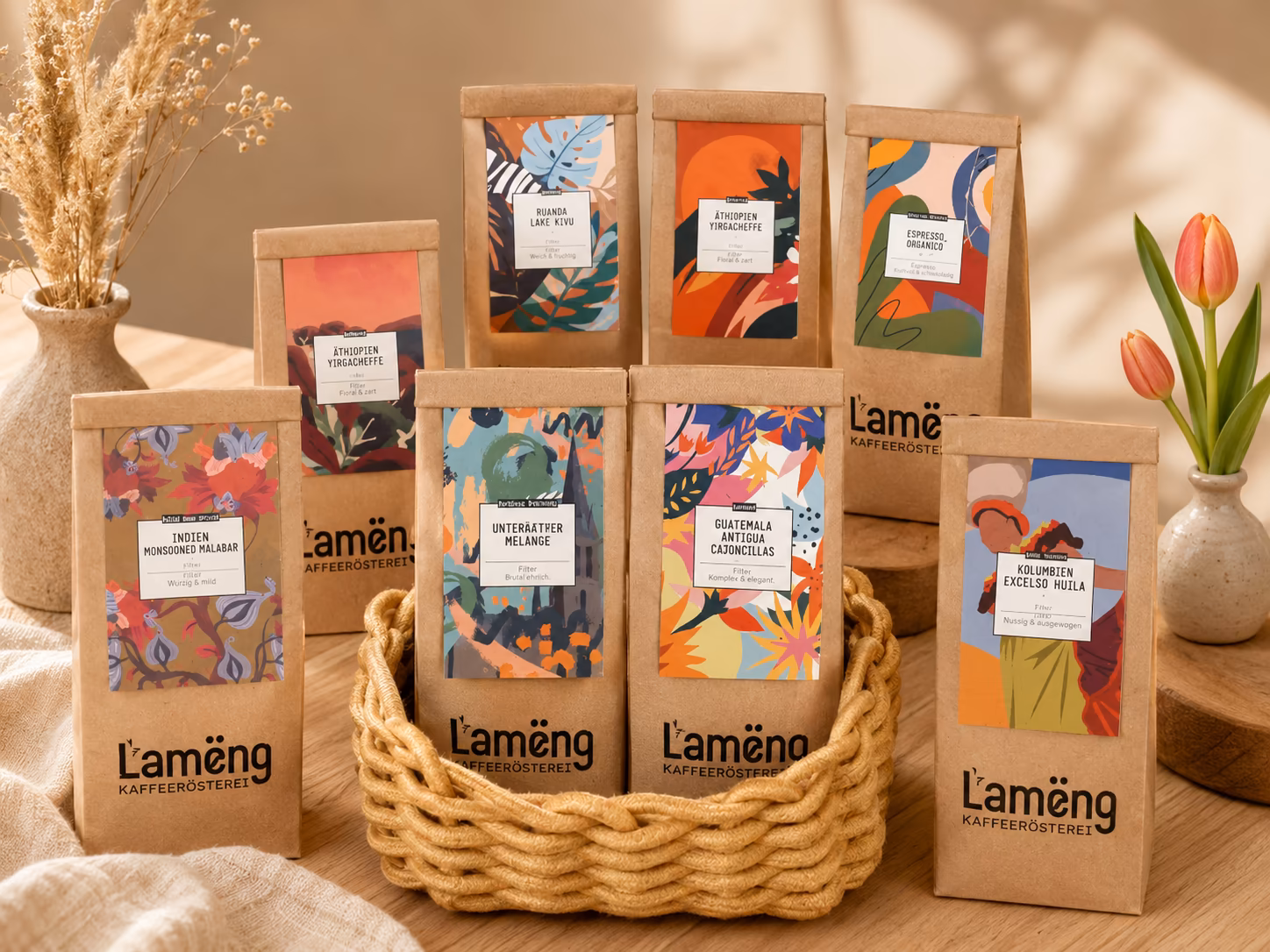 Lamëng-Kraftpapiertüten mit bunten Sorten-Etiketten in einem geflochtenen Korb auf einem Holztisch, daneben Tulpen und Trockenblumen in Vasen